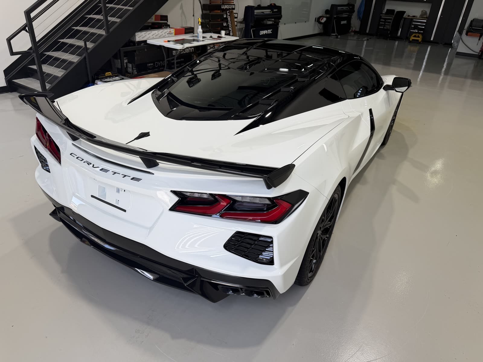 Rear view of a white C8 Corvette with a tinted roof blackout and ceramic coating