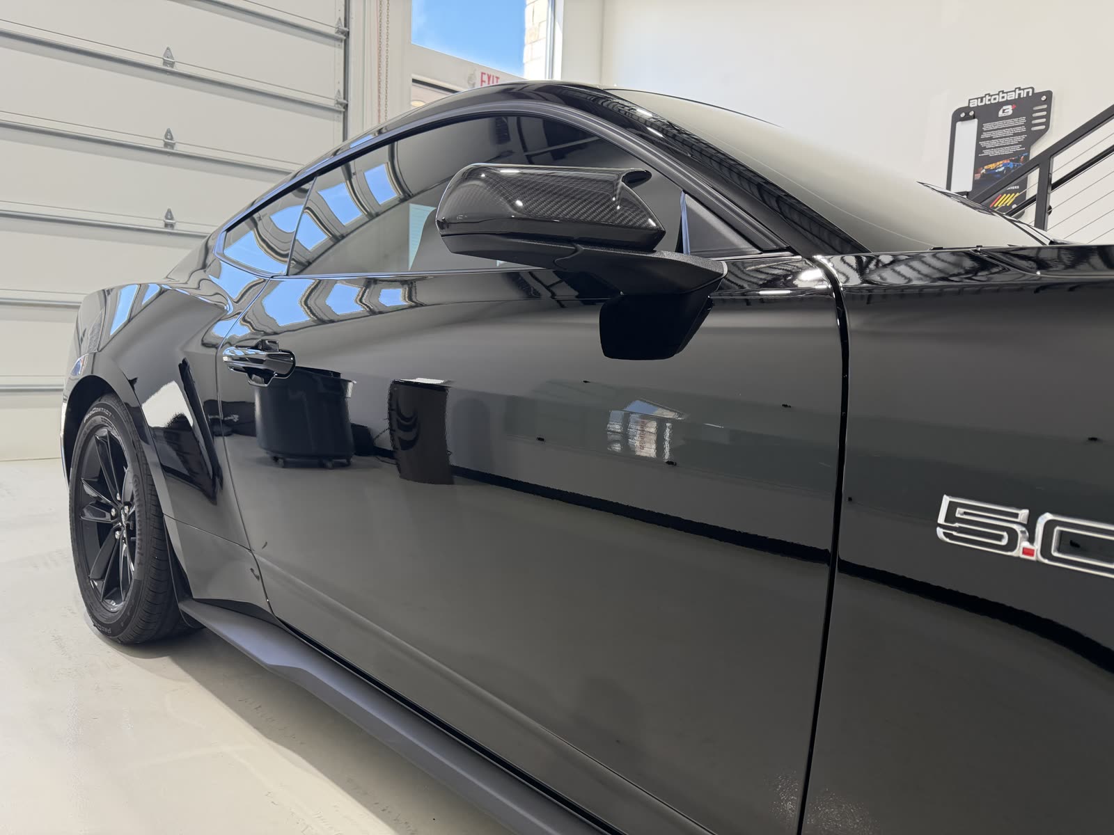Clear reflections in the black door paint of a ceramic coated Ford Mustang GT